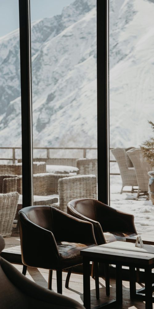 pexels-photo-7539892-7539892 Cozy restaurant interior with chairs, tables, and a snow-covered mountain view.